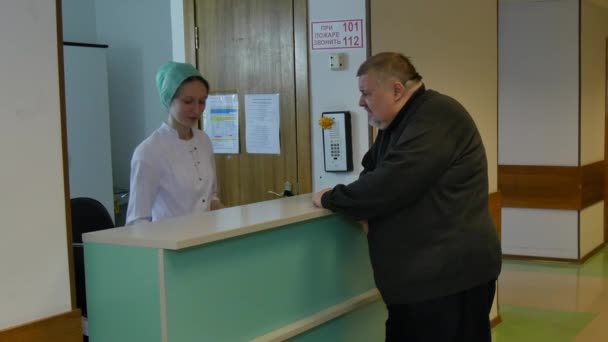 Enfermera toma tarjeta médica del gordo en la clínica . — Vídeos de Stock