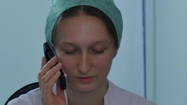 Медсестра разговаривает по мобильному телефону в клинике . — стоковое видео