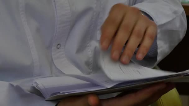 Hospital card in hands of doctor in white coat in modern clinic. — Stock Video