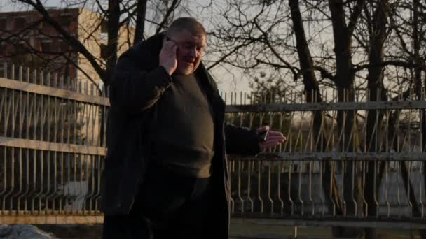 Um homem gordo falando ao telefone e muito nervoso na rua da cidade . — Vídeo de Stock