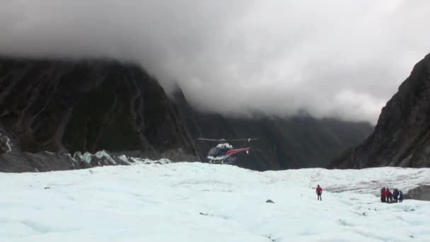 Les gens sont arrivés en hélicoptère sur le glacier dans les montagnes froides enneigées de Nouvelle-Zélande . — Video
