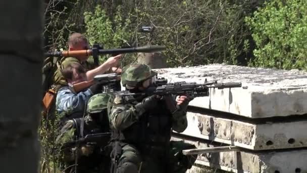 Soldado em uniforme militar com uma arma está em posição em uma casa destruída . — Vídeo de Stock