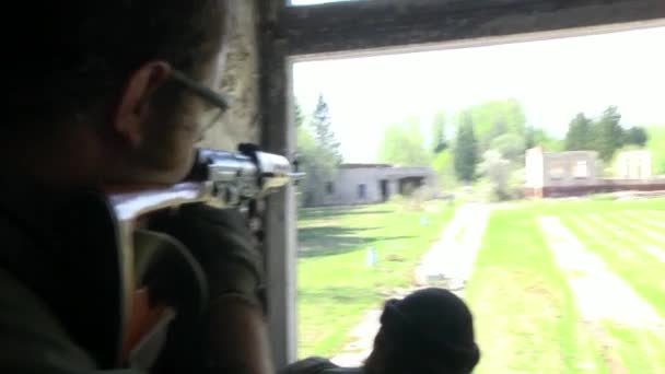 Żołnierz w mundurze wojskowym z bronią jest w pobliżu okna, zrujnowanego domu. — Wideo stockowe