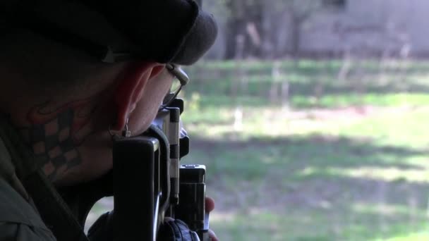 Soldat en uniforme militaire armé près d'une fenêtre de la maison en ruine . — Video