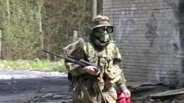 Harabe evin arka planında silahlı askerler var..