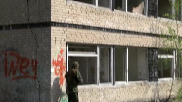 Soldat en uniforme militaire avec arme sur fond de maison en ruine . — Video