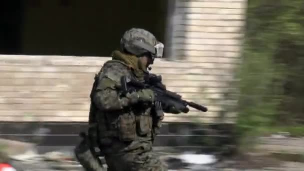 Soldater i militär uniform med vapen körs på bakgrund av förstört hus. — Stockvideo