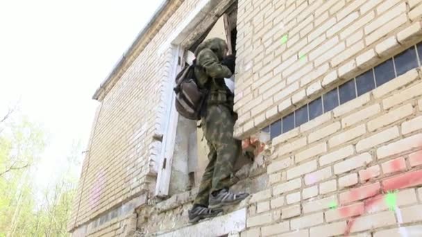 Airsoft muži ve vojenské uniformě se zbraní stoupá zničeného domu. — Stock video