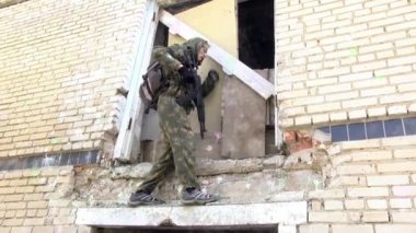 Airsoft erkekler bir silahla askeri üniformalı tırmanıyor harap evi.