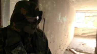 Bir silah ile askeri üniformalı askerler olduğu konumda yok edilen bir evde.