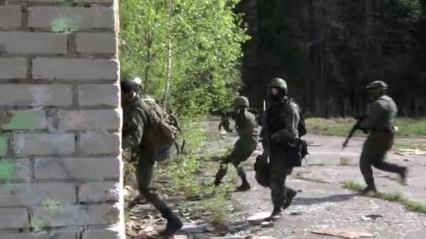 Vojáci ve vojenské uniformě s zbraní chodit na pozadí zničeného domu. — Stock video