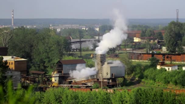 Buizen van fabrieksinstallaties rook onder de groene bomen en natuur in Alapajevsk. — Stockvideo