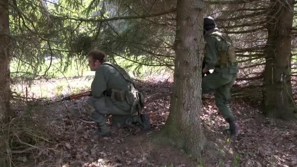 Людина в Армійське обмундирування зі зброєю, що ховається під дерево. — стокове відео