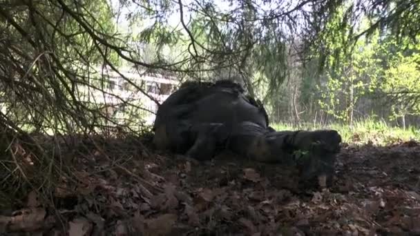 Hombre en uniforme militar con un arma se esconde bajo el árbol . — Vídeos de Stock