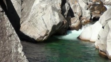 Verzasca dağının vadisindeki büyük taşların arasından sular akar..