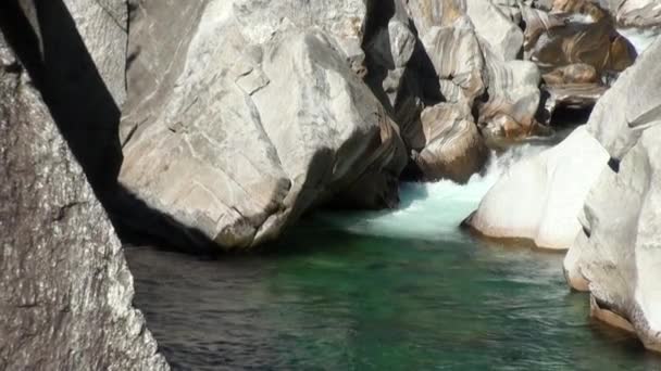 A água flui entre pedras enormes no vale do rio de montanha Verzasca. — Vídeo de Stock