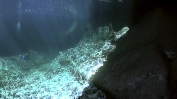 Camera operator in refraction of sunlight underwater in transparent river. — Stock Video