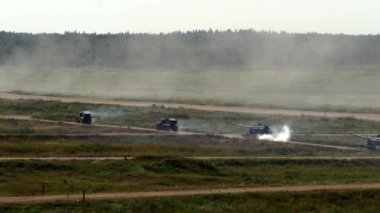 Askeri tanklar orman ve patlamalar arka plan üzerinde hareket ediyor.