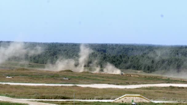 Military tank rides across field in background of forest at the Army Forum 2017. — Stock Video