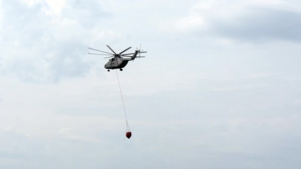 Helicóptero de carga con cucharón de vertedero suspendido está volando desde el depósito. — Vídeos de Stock
