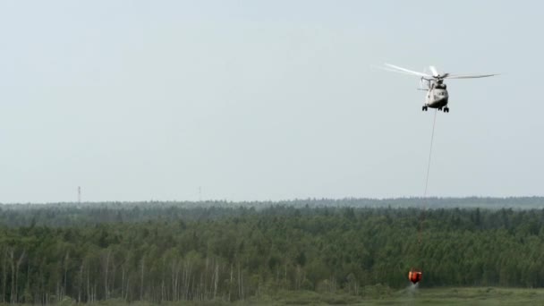 Hasičská helikoptéra s pozastavenou přelivu naběračku nákladní bere vodu z nádrže. — Stock video