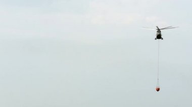 Sızıntı kepçesi askıya alınmış kargo yangın helikopteri rezervuardan uçuyor..