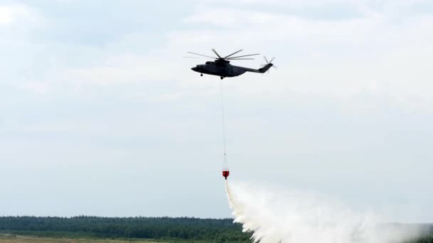 Rojo colgando cucharada de un helicóptero de fuego arroja agua sobre fondo gris cielo . — Vídeos de Stock