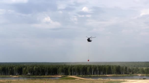 Helikopter strażacki ładunku z kadzi zawieszone przelew trwa wody ze zbiornika. — Wideo stockowe