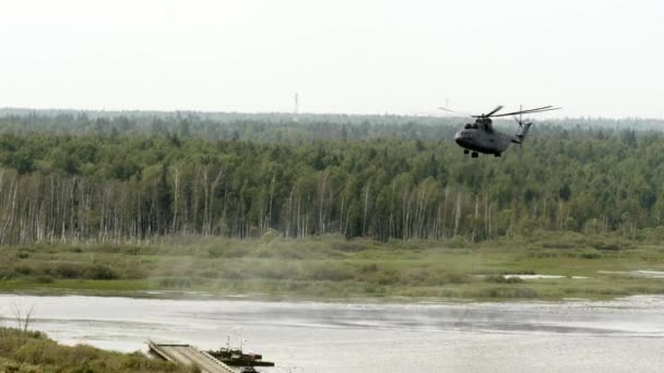 Грузовой пожарный вертолет с подвешенным ковшем забирает воду из резервуара . — стоковое видео