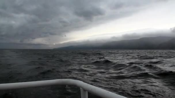 在天空中的深灰色云雾和贝加尔湖的风暴背景上的游艇铁轨. — 图库视频影像