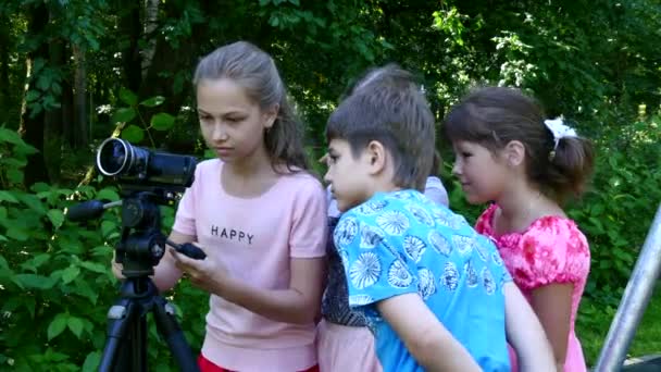 Kinder mit Videokamera auf Stativ drehen Filme über die Natur des grünen Parks. — Stockvideo