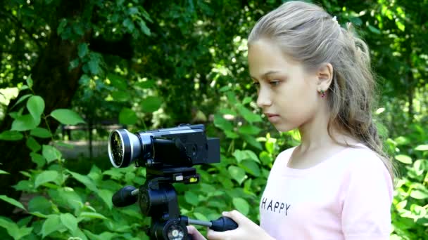 Giovane ragazza guarda in videocamera su sfondo di sfondo verde parco . — Video Stock