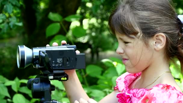 Mladá dívka vypadá na video kameru na pozadí pozadí zelený park. — Stock video