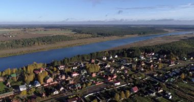 Arka planda gökyüzü ve büyüleyici manzara manzaralı bulutlarla çevrili bir nehir üzerinde evleri ve bahçeleri olan inanılmaz bir köy manzarası. Açık hava iklimi kavramı.