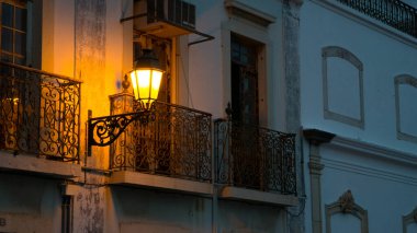 Geceleri Faro, Algarve, Güney Portekiz 'de balkonları olan tipik eski evler sadece sarı bir sokak lambasıyla aydınlatılıyor..