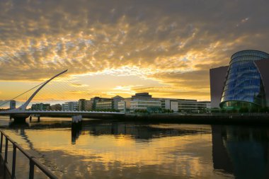 Dublin, İrlanda 'nın günbatımı silueti Liffey nehrine, Samuel Beckett Köprüsü' ne ve Kongre Merkezi 'ne bakıyor..