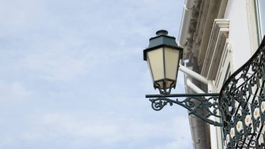 Faro, Algarve Bölgesi, Portekiz 'deki bir binanın balkonunda eski bir demir gaz lambası. Mavi gökyüzü ve beyaz bulutlar arkasında.