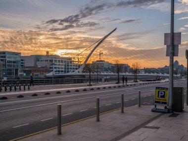 Dublin, İrlanda 'nın günbatımı silueti Liffey nehrine bakıyor, Samuel Beckett Köprüsü, harp köprüsü olarak da bilinir..
