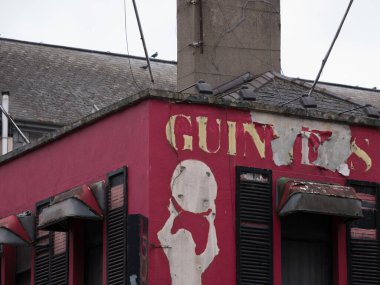 Old, abandoned, Irish pub in Dublin, Ireland with peeling Guinness paint and dirty window canopies clipart