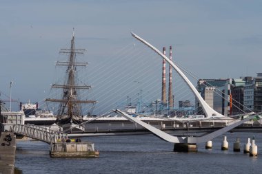 Dublin, İrlanda 'daki Liffey Nehri' nin aşağısına Samuel Beckett Köprüsü, havuzcu bacaları ve kıtlık gemisi ile sıkıştırılmış bakış açısı. 
