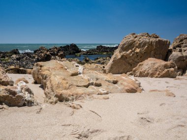 Yazın güneşli bir günde Portekiz plajında beyaz mermer çizgili doğal kumtaşı kayaları