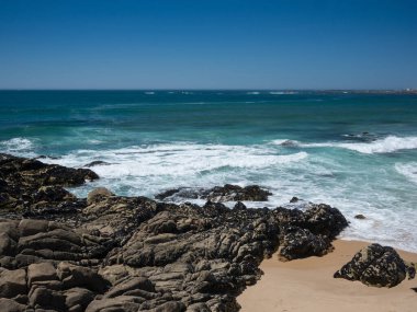 Güneşli bir günde, güzel kayalık plaj. Açık turkuaz mavi su ve mavi bulutsuz gökyüzü Vila do Conde, Porto, Portekiz 'de.