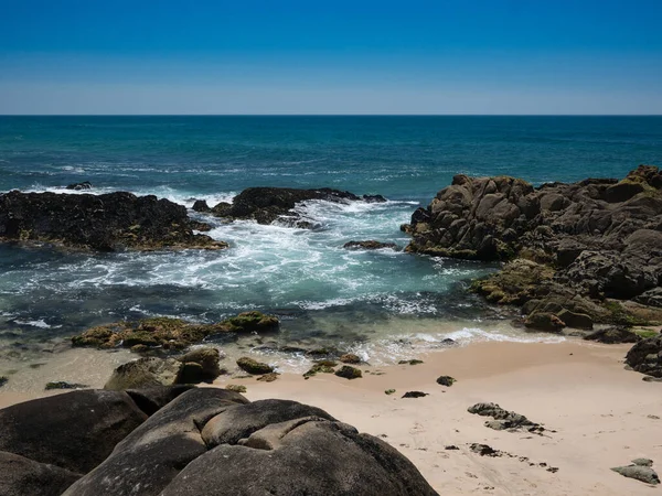 Clear turquoise water lapping on shore of sandy beach in Portugal in summer. Blue cloudless sky.