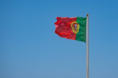 Mavi gökyüzüne karşı Portekiz bayrağı. Boşluğu sola kopyala.