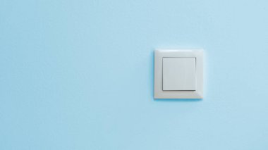Mavi duvarda solda kopyalama alanı olan beyaz elektrik düğmesi.