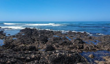 Vila do Conde, Portekiz 'de mavi bulutsuz gökyüzü ile mavi Atlantik okyanusuna doğru kayaların üzerinden bakıyorum. 