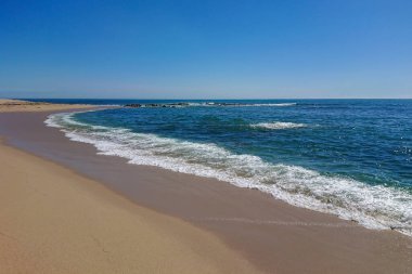 Güneşli bir yaz gününde mavi gökyüzü olan Portekiz 'in boş kumlu sahilleri.,