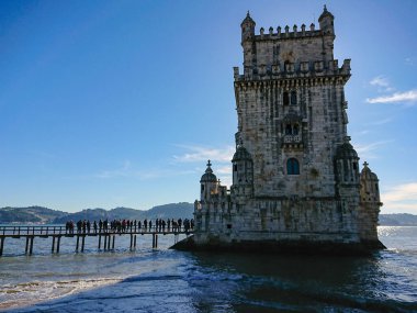 Lizbon, Portekiz 'deki Belem Kulesi. Ana kule ve turistler güneşli bir günde mavi gökyüzüne karşı kuyruğa giriyorlar