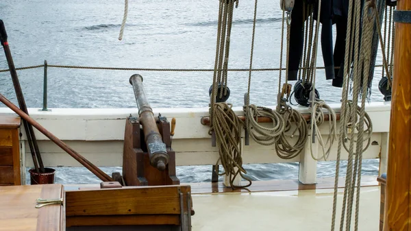 Vintage ship\'s cannon on the deck of a sailing ship with ropes and rigging.