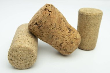 Beyaz arka planda üç farklı boyutta şarap mantarı, yumuşak gölgeli.